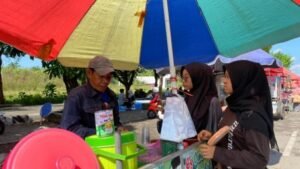 Seorang pedagang kecil melayani pembeli di kawasan CFD Kediri. Bagi para pedagang, keramaian CFD setiap akhir pekan menjadi sumber  tambahan penghasilan di tengah meningkatnya kebutuhan hidup. 